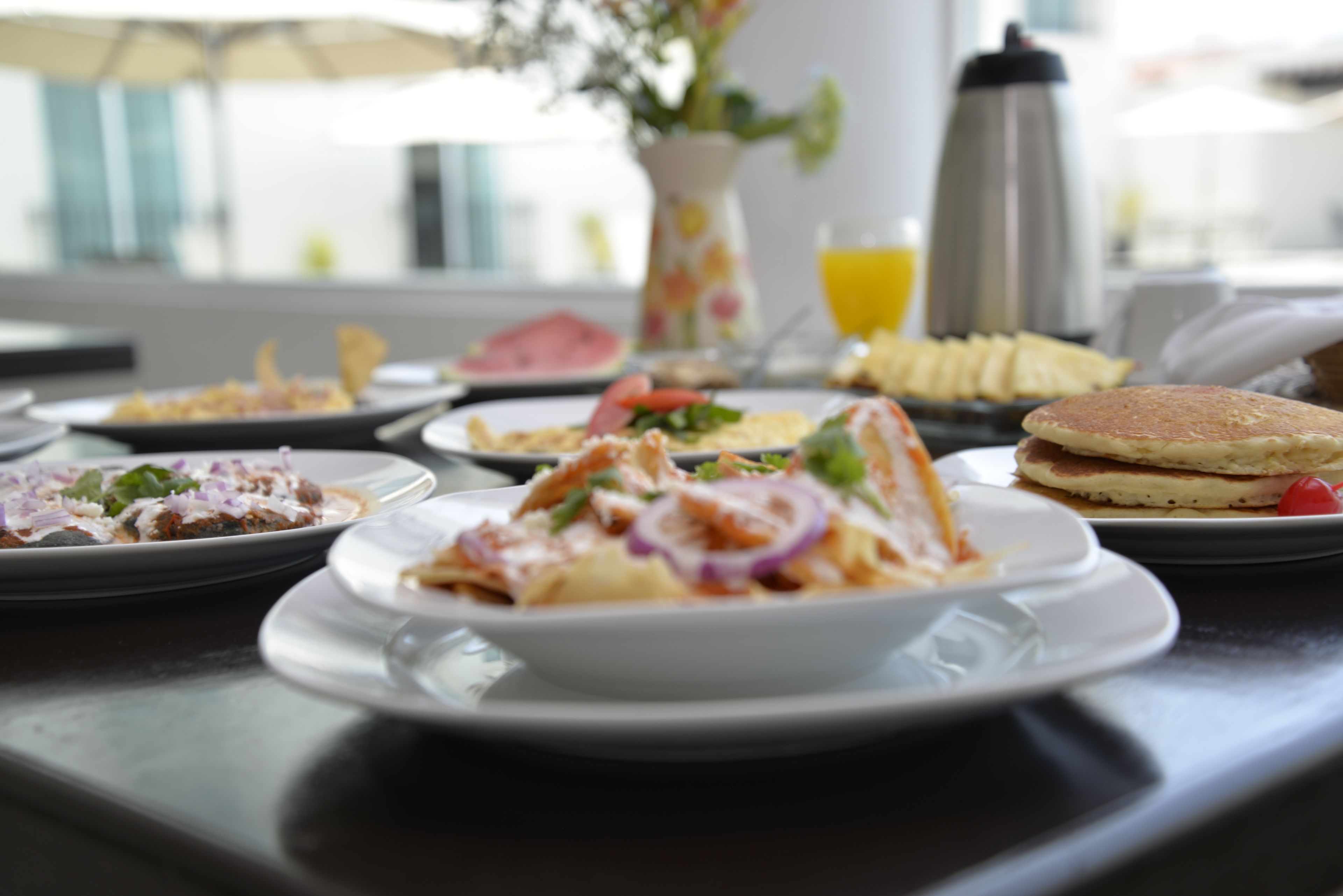 A breakfast table with various dishes, including pancakes, a salad, and a fruit plate.