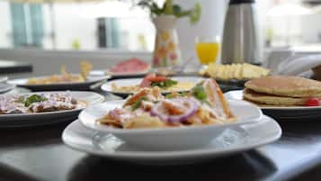 A breakfast table with various dishes, including pancakes, a salad, and a fruit plate.