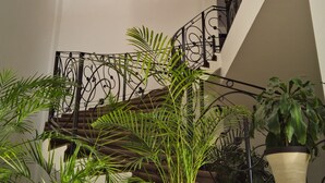 A multi-level interior with a spiral staircase, potted plants, and a decorative metal railing. - Hotel Osalle Inn (Chignahuapan)