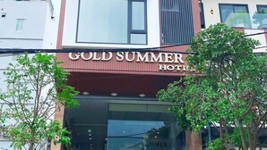 L’extérieur de l’hôtel Gold Summer présente une entrée bien visible, un escalier menant à la porte et un panneau indiquant les coordonnées.
