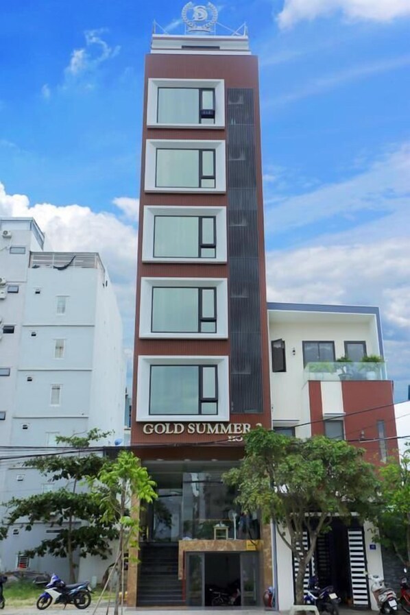Un immeuble à plusieurs étages dont la façade porte l’inscription « GOLD SUMMER ».