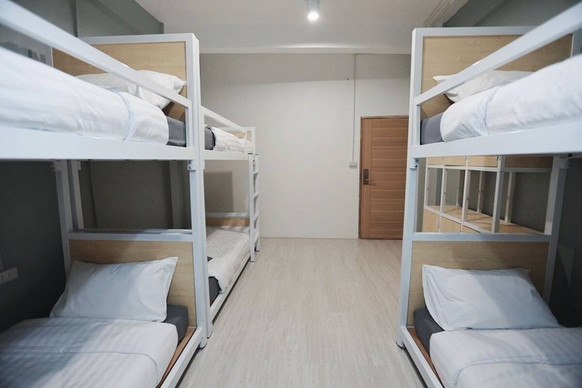A room with bunk beds, wooden flooring, and a door.