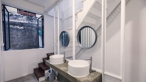 A modern bathroom with two sinks, a window with a view, and a textured wall. - Local Time Bangkok - Hostel (Bangkok)