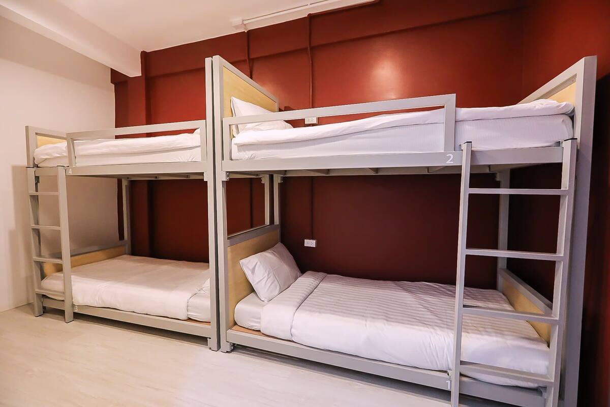 A bunk bed room with two bunk beds, each with a ladder and a mattress.