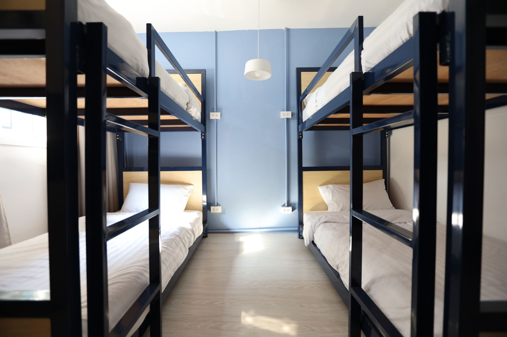 A room with bunk beds, a light fixture, and a wooden floor.