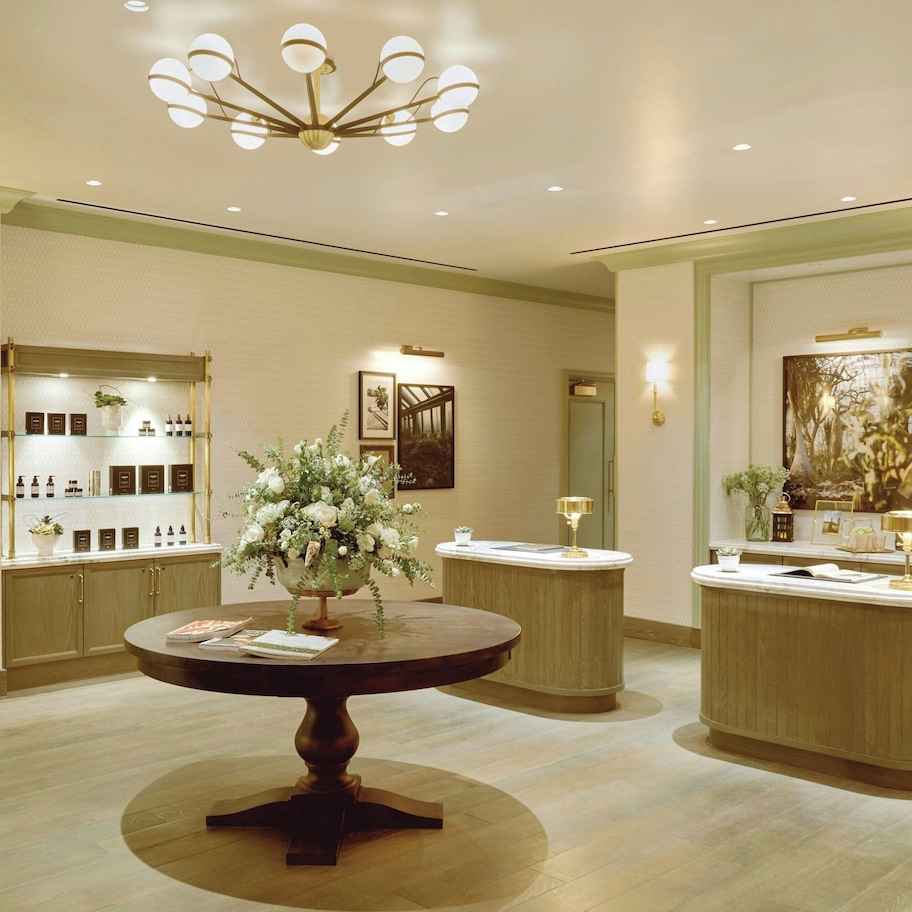 A hotel lobby with a round table, a reception desk, and a display of toiletries.