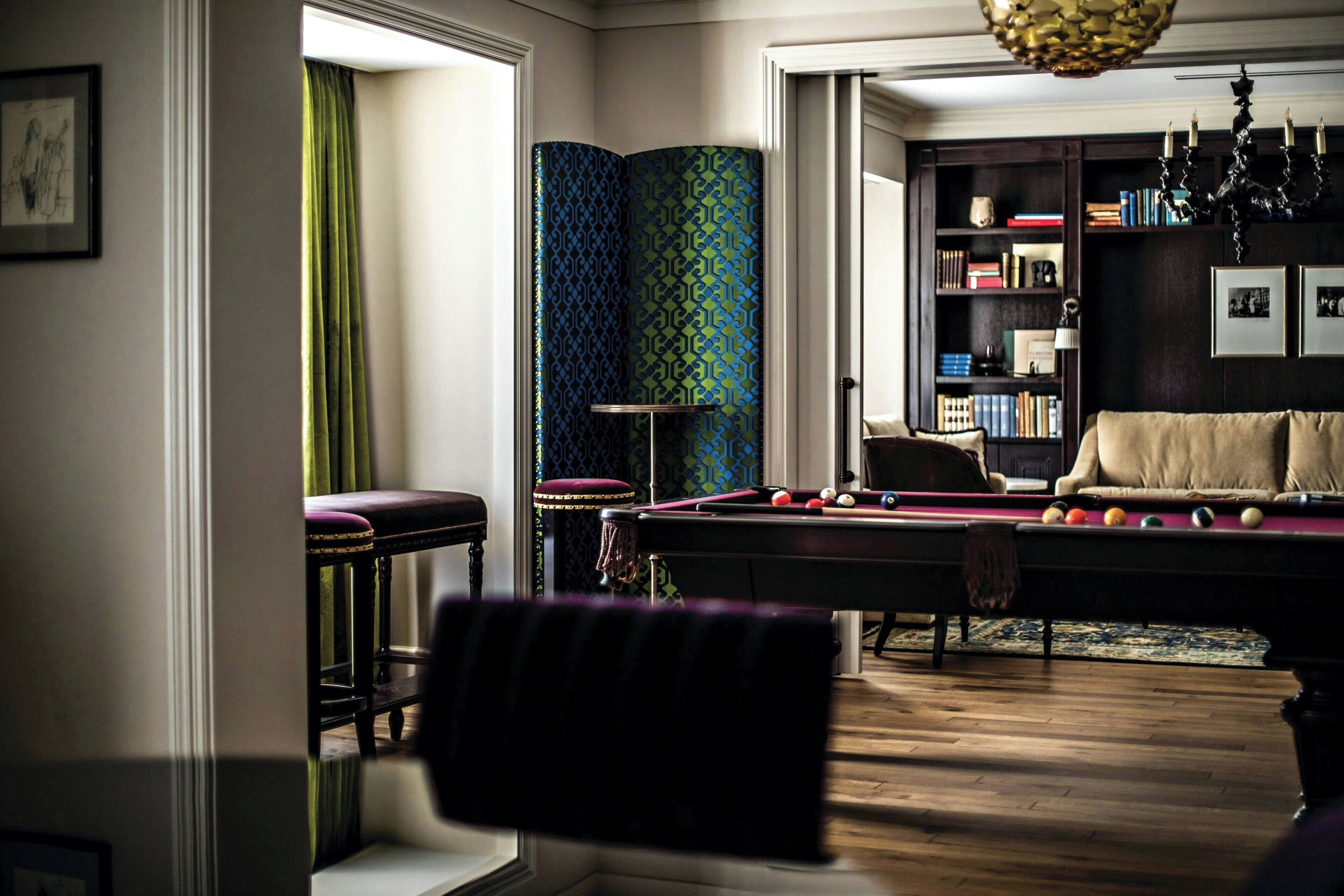 Une salle de billard équipée d’une table de billard, d’un canapé et d’une bibliothèque.