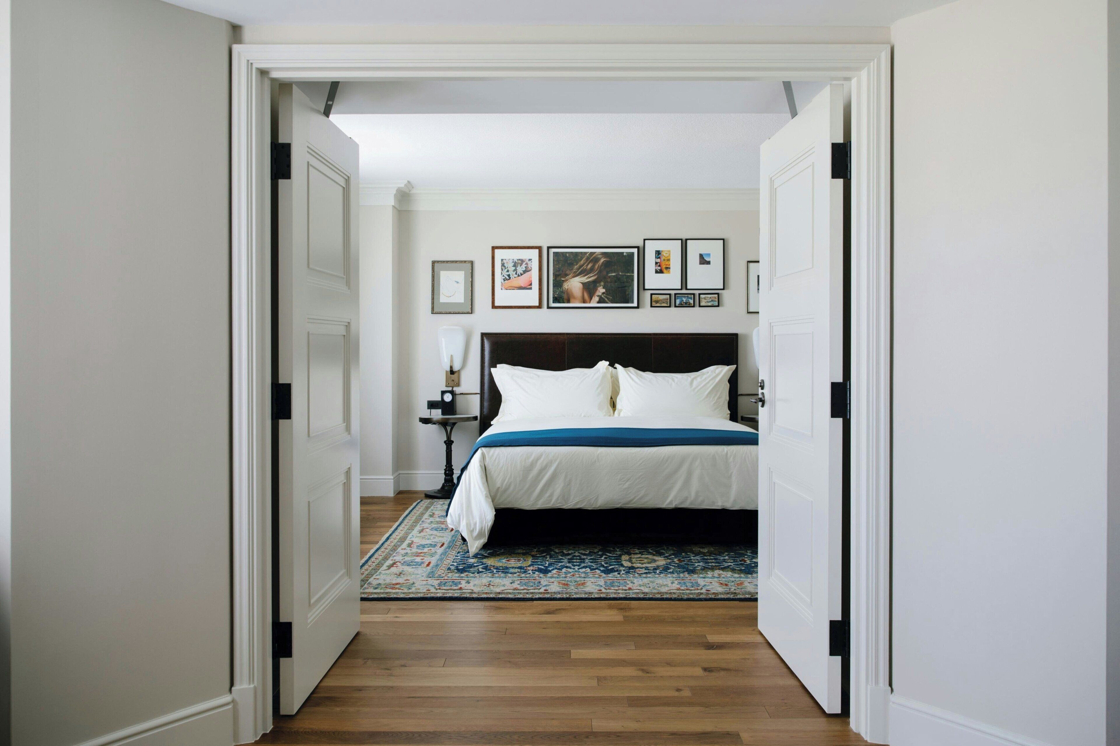 Une chambre à coucher avec un lit, une table de chevet et un mur orné de tableaux.