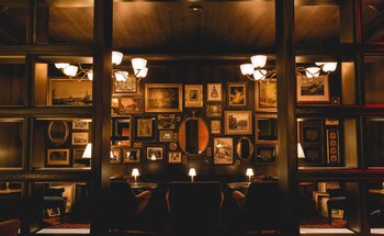 A dimly lit room with a grand piano, plush red upholstered chairs, and a large window with curtains. at The Reserve at Park MGM