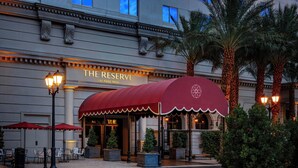A hotel exterior with a red awning, outdoor seating, palm trees, and a sign reading "The Reserve at Park MGM." - The Reserve at Park MGM (Las Vegas)