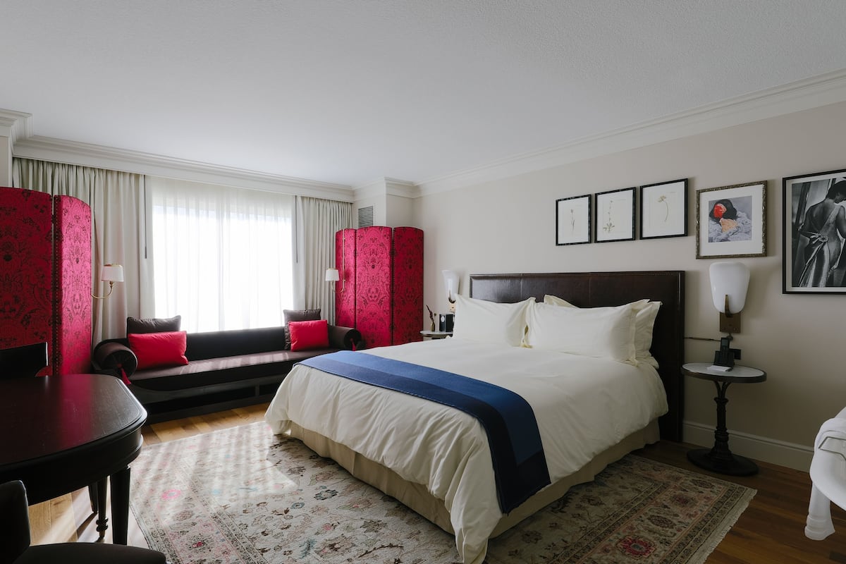 Habitació d'hotel amb un llit gran, un sofà, una taula de dinar i una petita taula auxiliar.