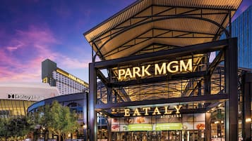 En byggnad i flera våningar med skyltar som visar "PARK MGM" och "EATALY", med en modern arkitektonisk design som kännetecknas av ett framträdande utskjutande tak och en glasfasad.