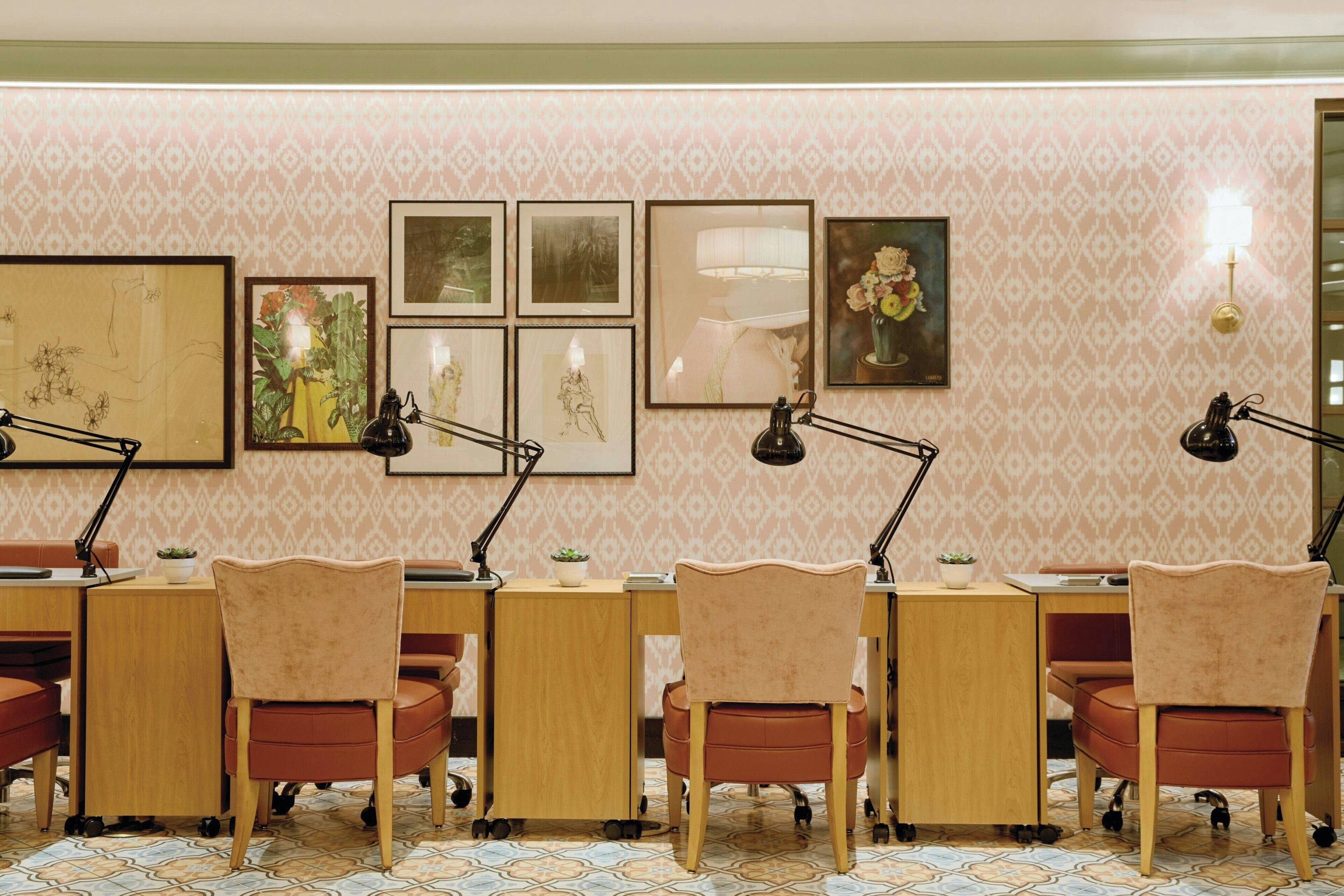 A conference room with a patterned wallpaper, multiple desks with chairs, and wall-mounted lamps.