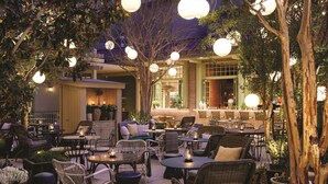 An outdoor seating area with wicker furniture and hanging spherical lights. - The Reserve at Park MGM (Las Vegas)