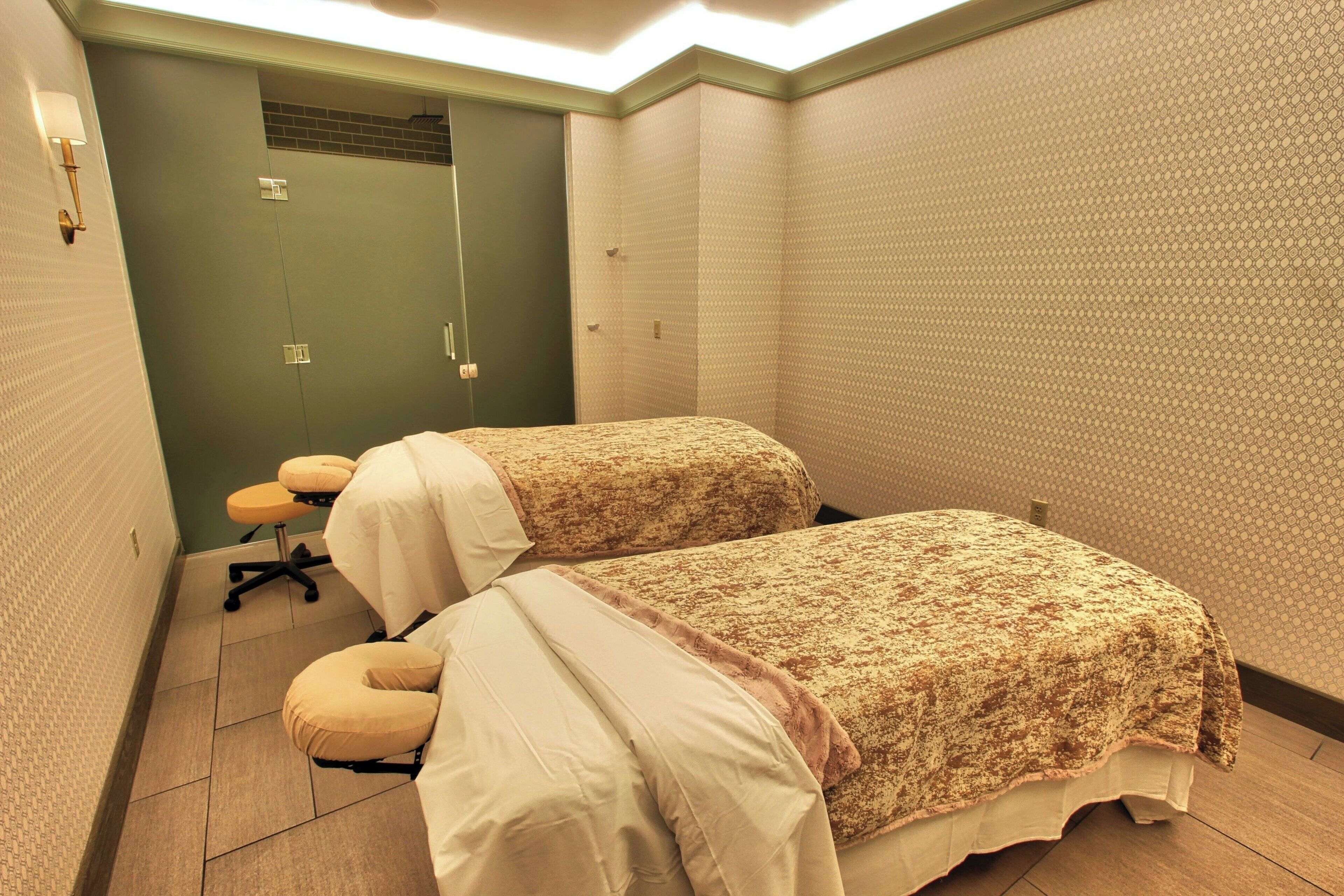 A small, private room with two beds, a chair, and a door.