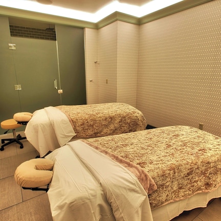 A small, private room with two beds, a chair, and a door.