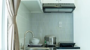 A compact kitchen with a sink, a rice cooker, and a stove.