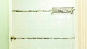A bathroom with a white toilet, a bathtub, and a shower area.