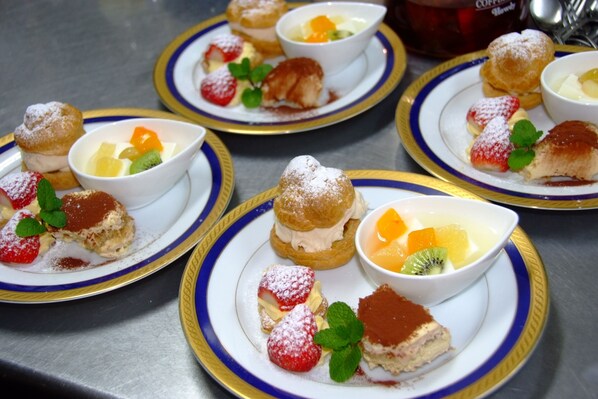 A table with plates of desserts, including pastries and fruit.