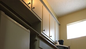 A kitchen with a refrigerator, microwave, and cabinets. - Red Carpet Motel (Edmond)