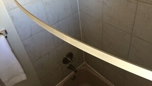 A bathroom with a shower area, a toilet, and a sink. - Red Carpet Motel (Edmond)