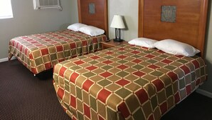 Ein Hotelzimmer mit zwei Betten, jeweils mit kariertem Bettbezug, einem Nachttisch mit Lampe und einer Wand-Klimaanlage.