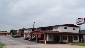 A motel with a red awning, a signboard, and several parked cars. - Red Carpet Motel (Edmond)