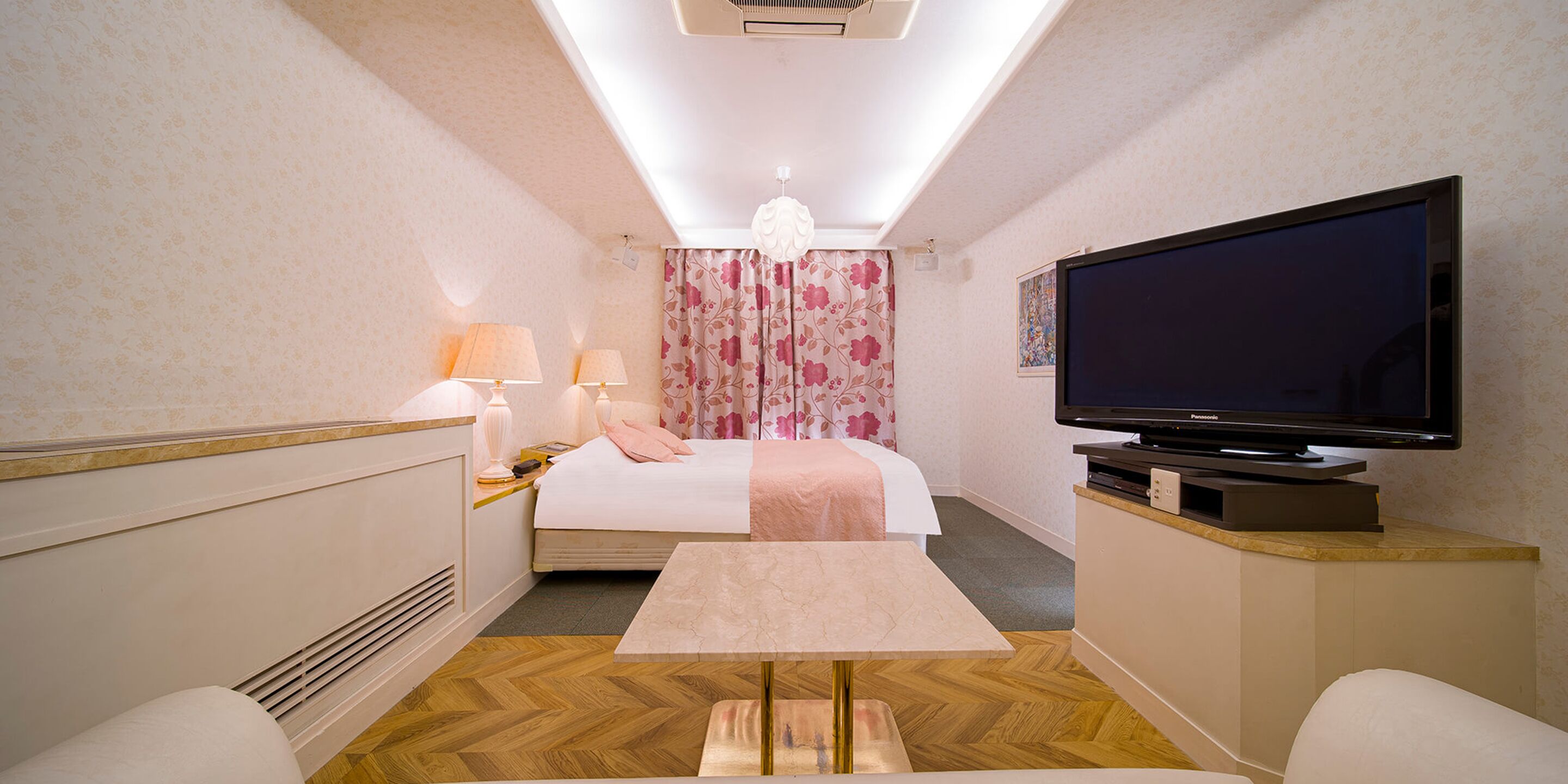 A hotel room with a bed, a television, a table, and a chair.