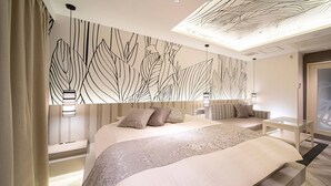 A modern hotel room with a large bed, a seating area, and a decorative ceiling. - HOTEL U's Kouroen – Adults Only (Nishinomiya)