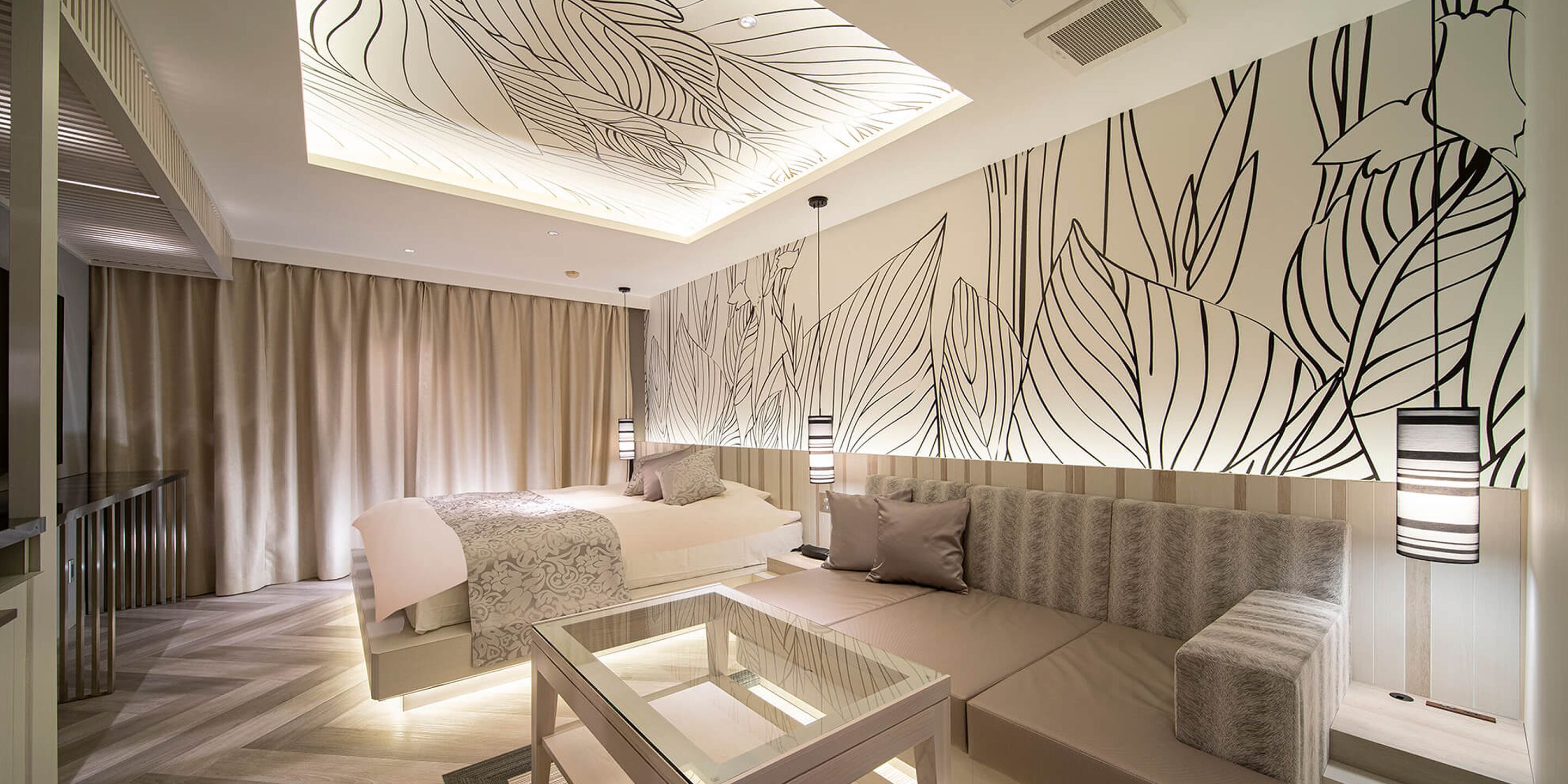 A modern hotel room with a bed, sofa, and a glass coffee table.