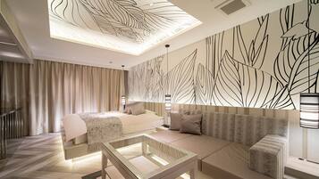 A modern hotel room with a bed, sofa, and a glass coffee table.