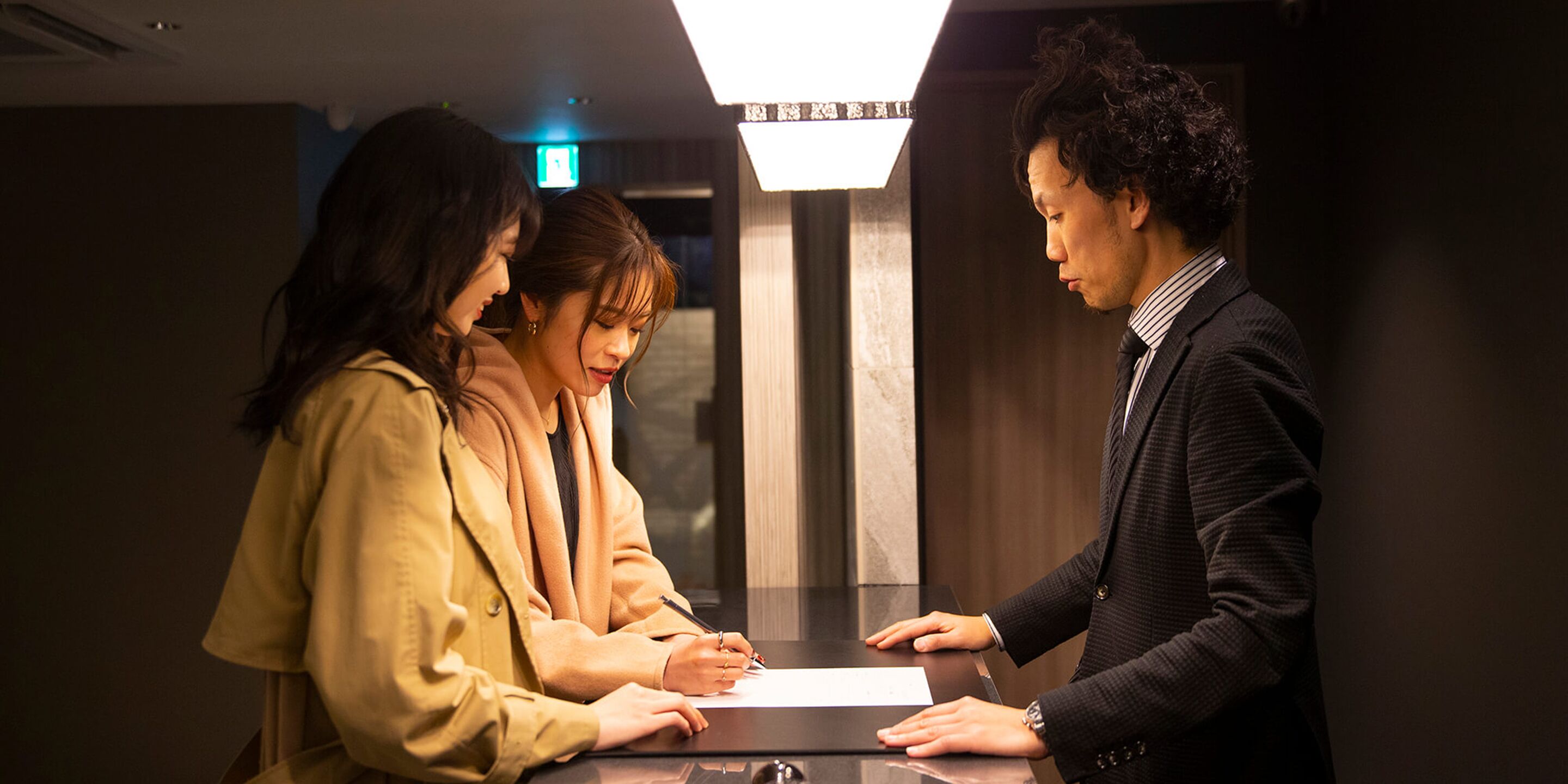 Una reception in un hotel con un design moderno, con un piano di lavoro per il check-in e un display digitale sopra.