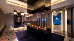 A modern hotel lobby with a central fire feature, seating areas, and a digital welcome screen. - HOTEL U's Kouroen – Adults Only (Nishinomiya)