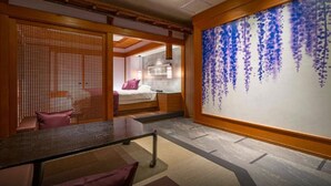 A hotel room with a bed, a desk, a chair, a large wall with a hanging floral design, and a wooden partition. - HOTEL U's Kouroen – Adults Only (Nishinomiya)