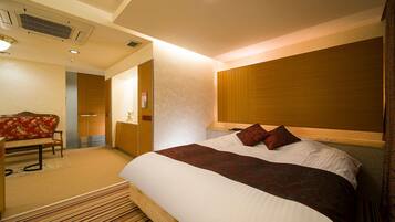 Quarto de hotel com uma cama grande, cabeceira de madeira, um banco e uma escrivaninha.