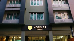 Un immeuble d’hôtel à plusieurs étages, sur lequel on peut lire l’inscription « HÔTEL 99 (YANGON) ».