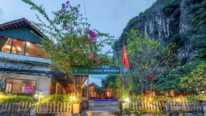 A gated entrance to a property named 'TAM COC ECO FIELD HOMES' with a sign, a flag, and a staircase leading to the main building. - Tam Coc Eco Field Homes (Nam Hoa Lu)