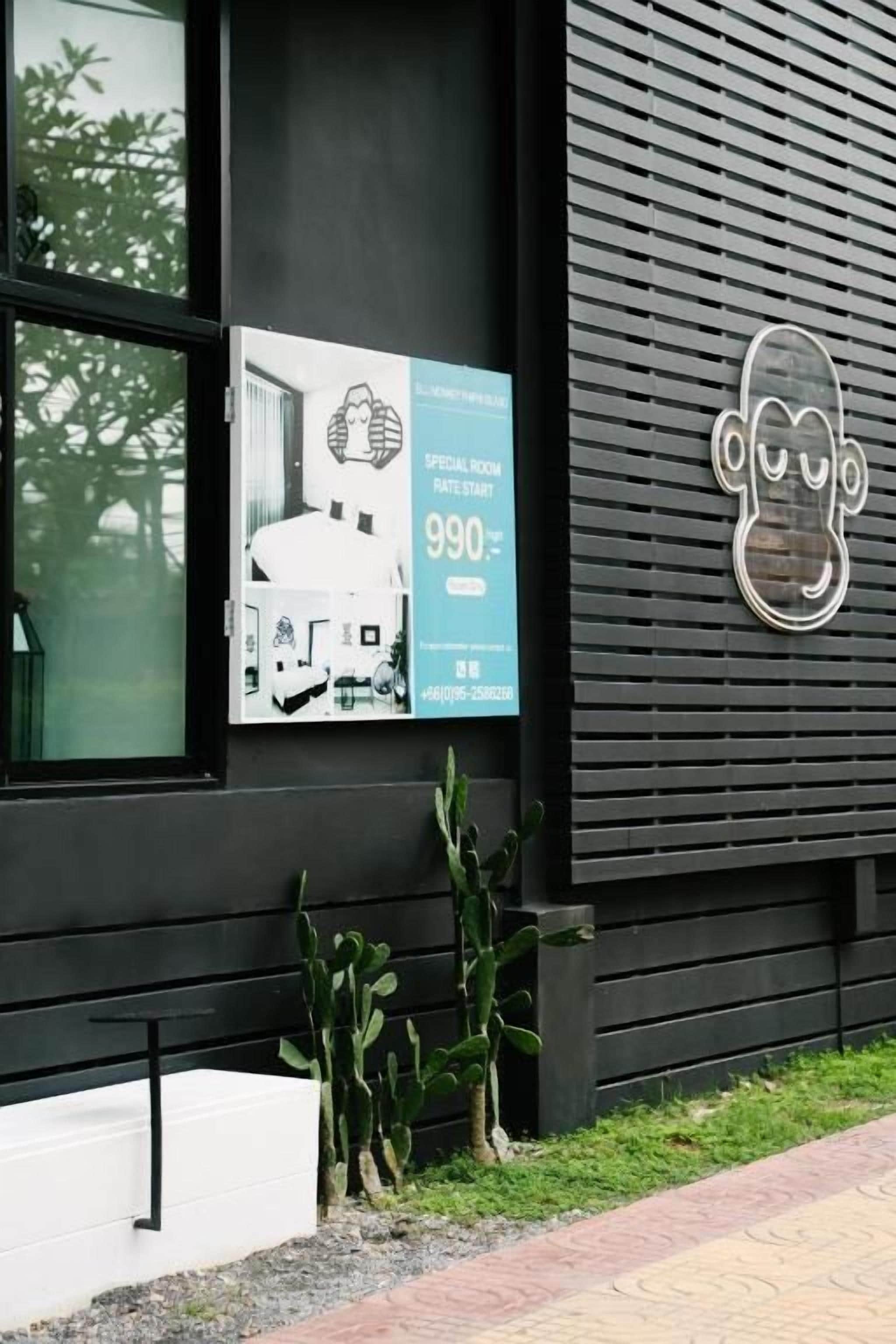 A building with a black exterior, a poster advertising a special room rate, and a cactus plant in front.