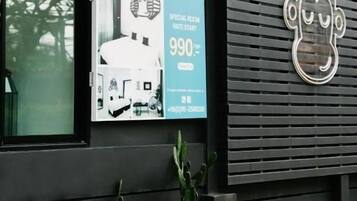 A building with a black exterior, a poster advertising a special room rate, and a cactus plant in front.