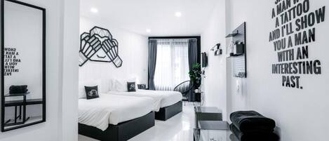 A modern hotel room with a large bed, a desk, and a mirror. There is a wall with a motivational quote and a framed picture.