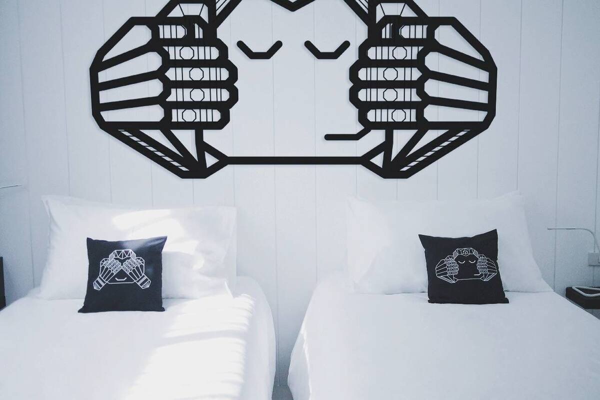 Une chambre d’hôtel avec deux lits, chacun agrémenté d’un oreiller orné d’un motif graphique.
