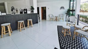 Eine moderne Hotellobby mit einer Rezeption, Korbstühlen und einem schwarz-weißen Teppich.