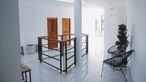 Ein geräumiger, moderner Innenraum mit hohen Decken, Holztüren und einer großen Pflanze.