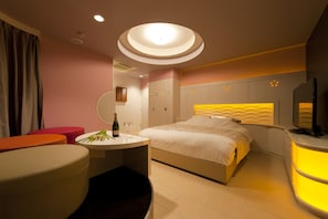 Una habitació d'hotel moderna amb un llit, una taula de nit i una petita zona de seients amb una taula rodona.