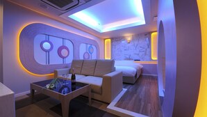 A modern hotel room with a sofa, a small table with a bottle and glasses, and a bed. - HOTEL IRIS - Adult Only (Fujisawa)