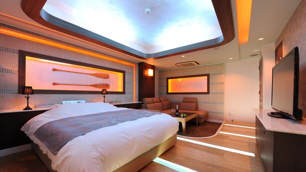 A modern hotel room with a large bed, a seating area, and a television. - HOTEL IRIS - Adult Only (Fujisawa)