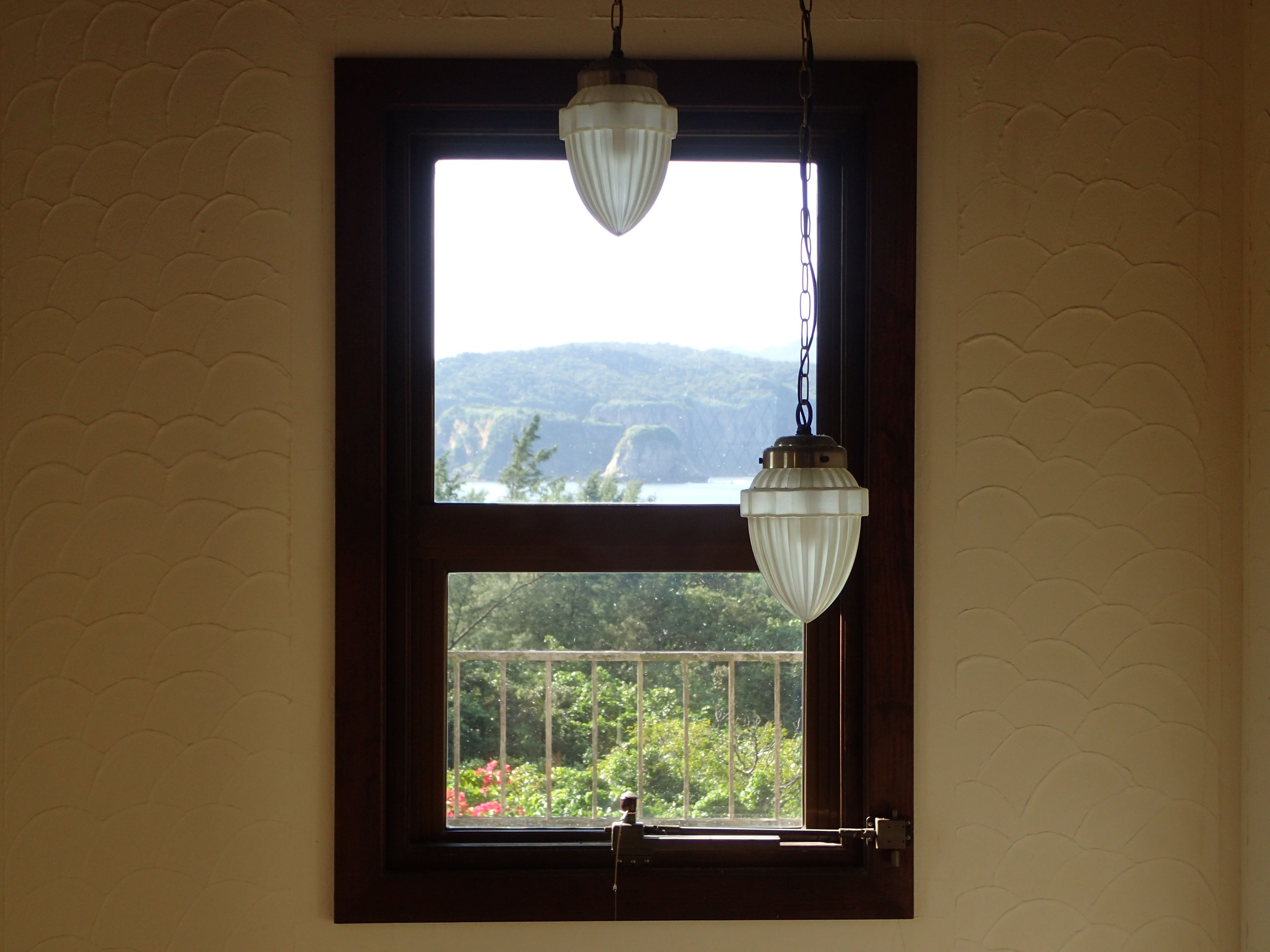 A window with a view of a mountainous landscape and a hanging light fixture.