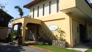 A two-story building with a yellow facade, a tiled roof, and a sign that reads "Maya Su Ku". - MaYaGuSuKu RESORT (Taketomi)