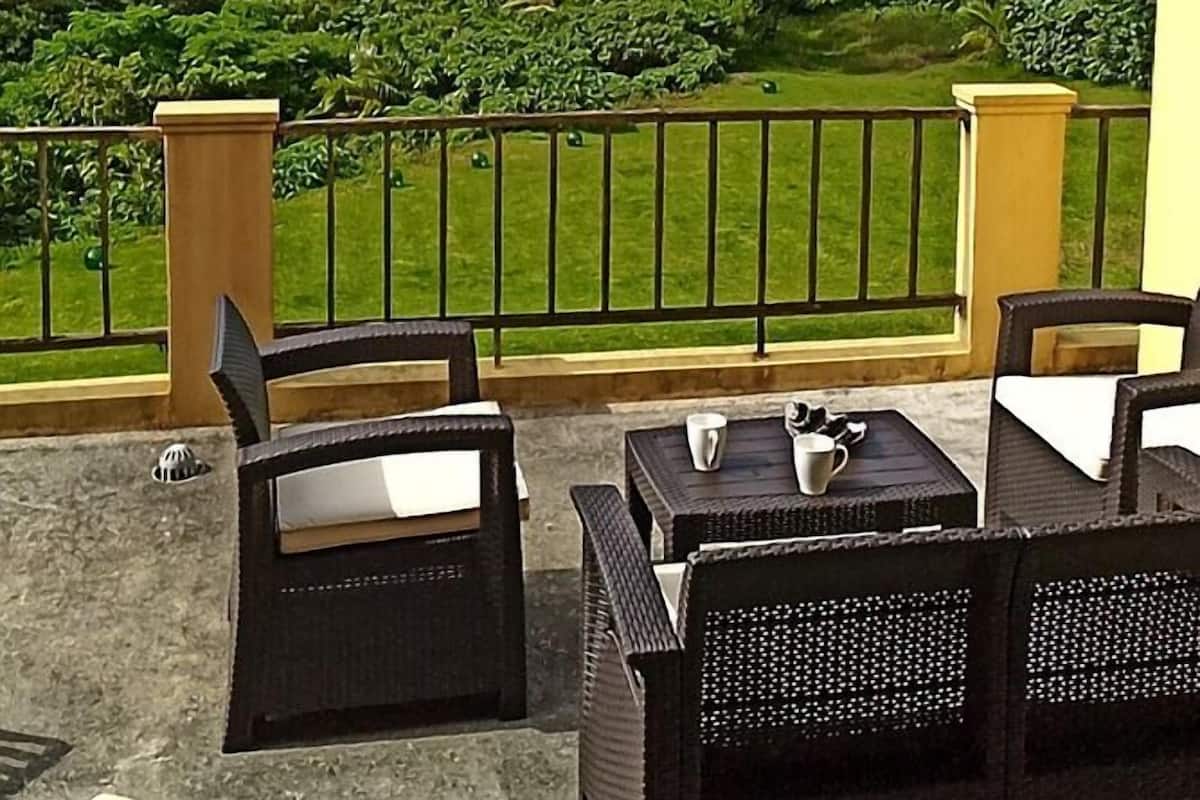 A terrace with outdoor furniture, a view of a lake, and surrounding greenery.