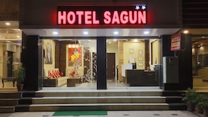 The entrance of Hotel Sagun with a reception desk, potted plants, and a colorful interior visible through the glass doors. - Hotel Sagun (Jaipur)